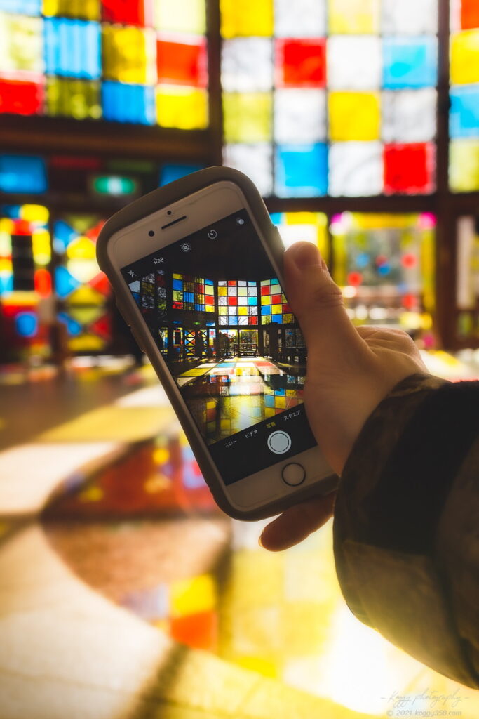 於大公園のこのはな館の「このはな彩」で、日中の館内でスマホに写るステンドグラス装飾の木漏れ日を撮影